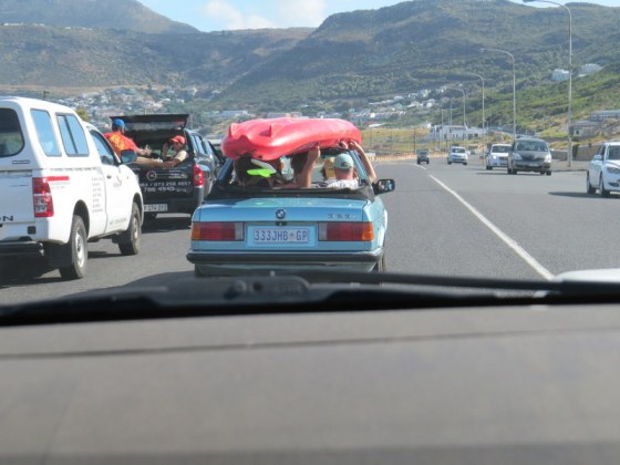 No roof to this car and the driver and passenger hanging on to the canoe so it doesn't fall off!